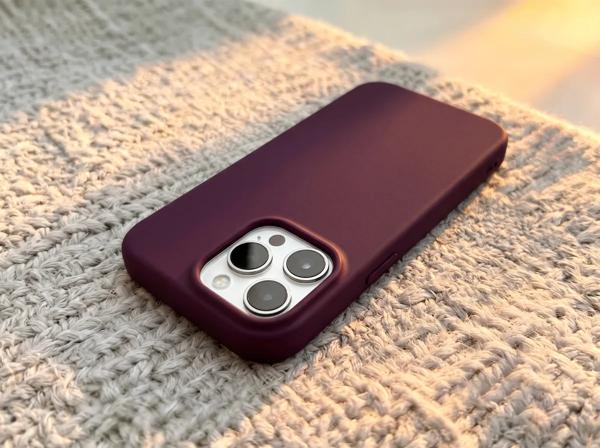 iPhone com capinha bordô sobre uma superfície de tecido bege